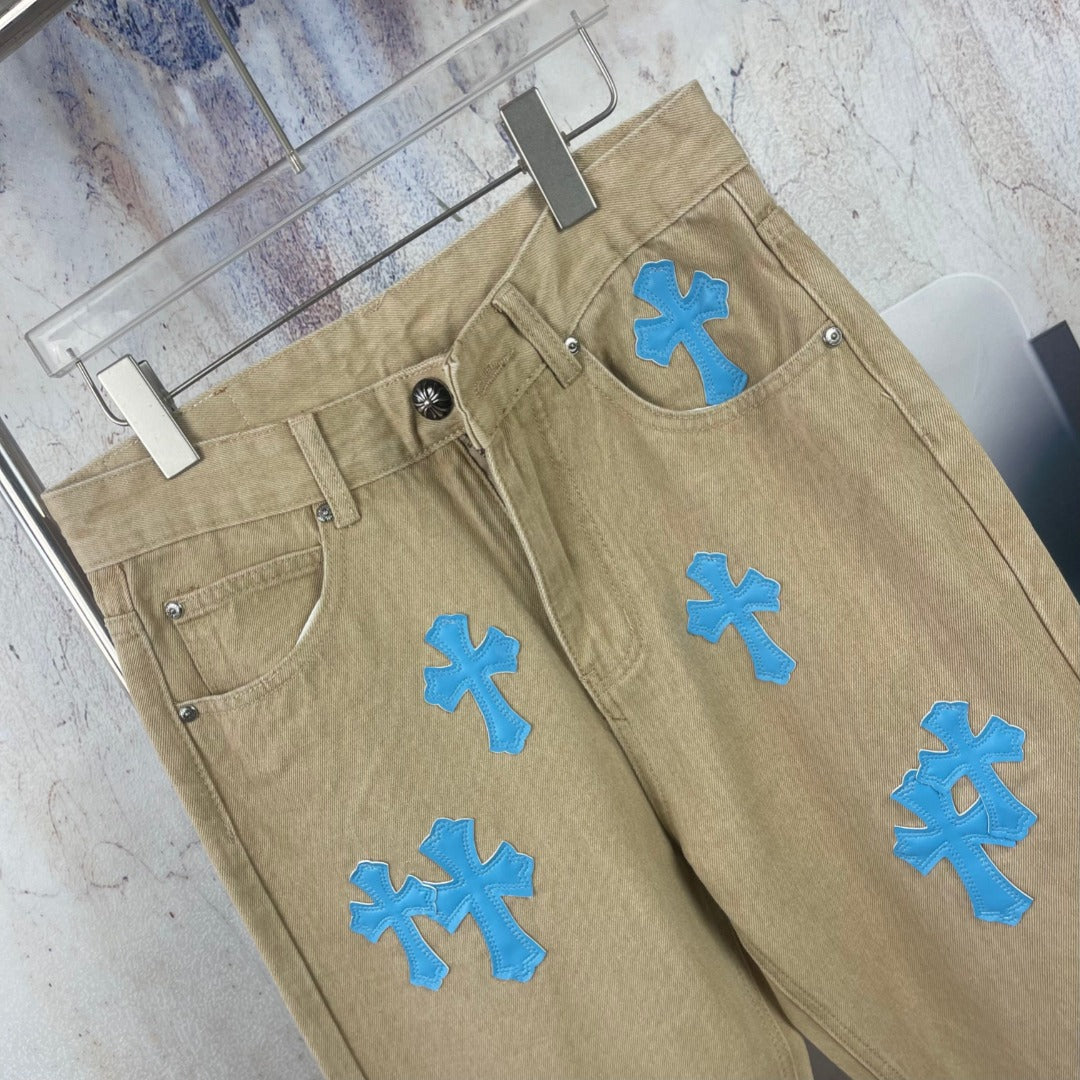 Tan straight-leg pants with blue cross-heart applique on front and back pockets