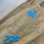 Beige pants back panel with blue cross-heart patches on curved yoke seam