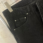 Black denim jeans with front patch pockets and metal rivets