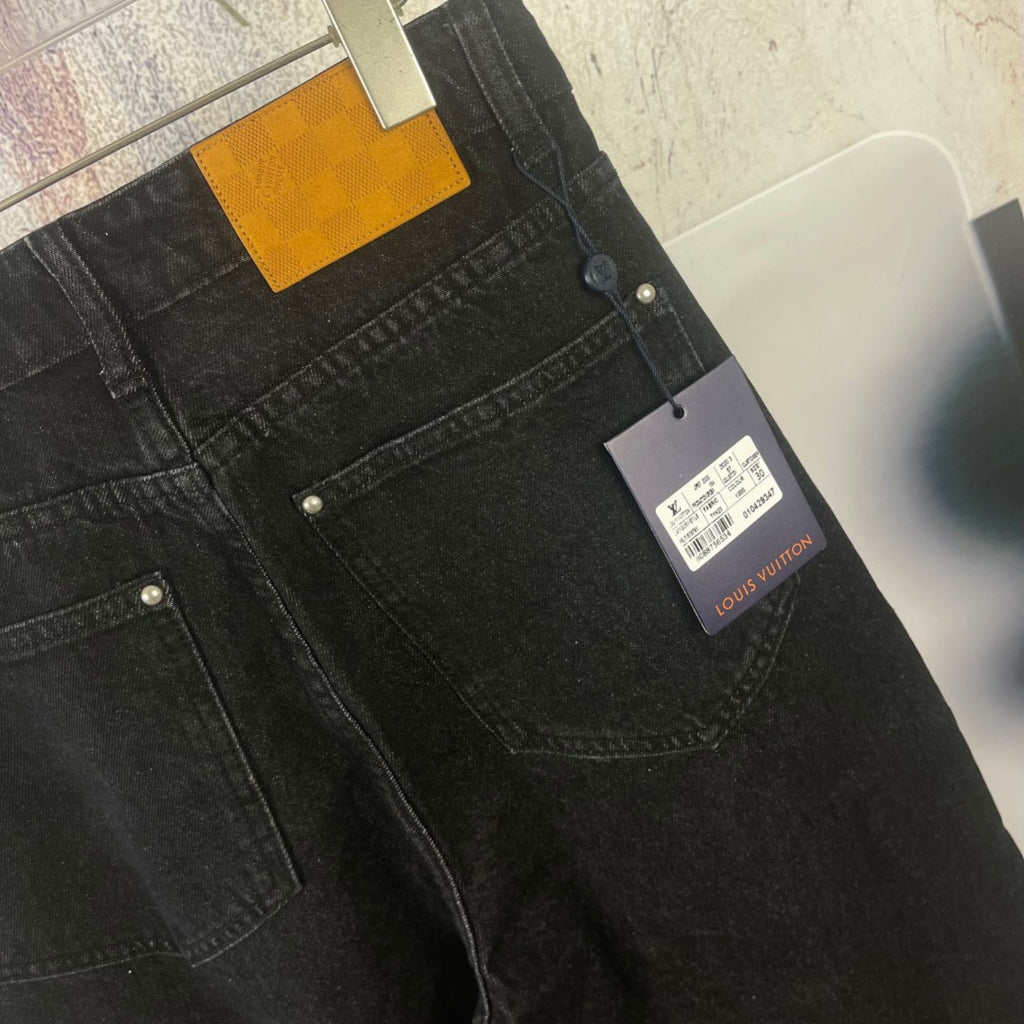 Black denim pants with belt loops, front buttons, and attached Louis Vuitton tag