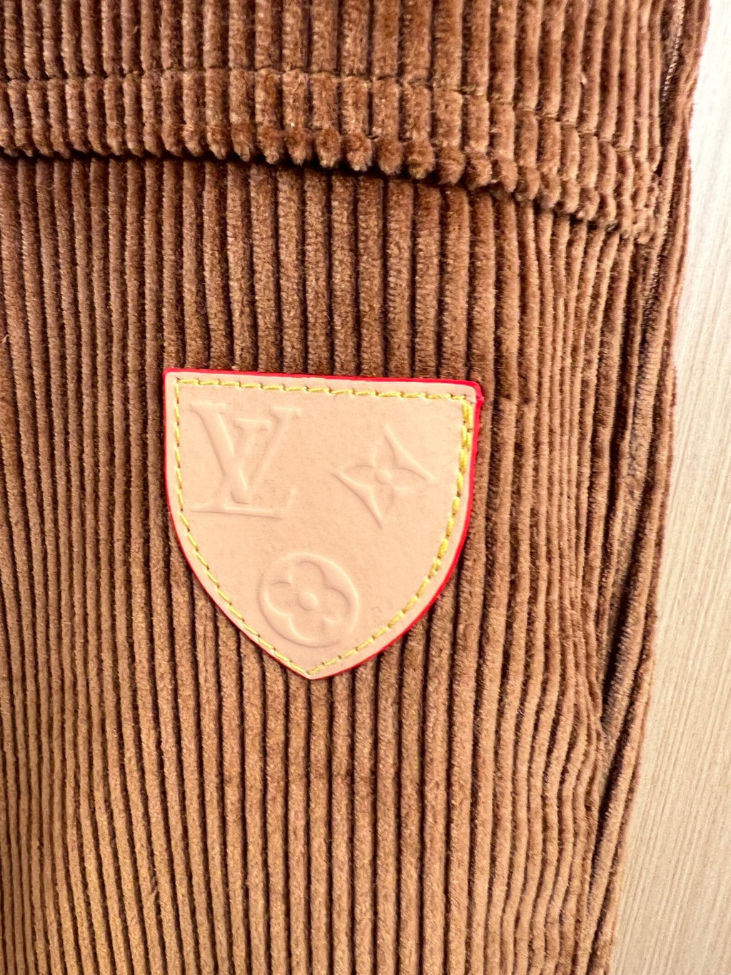 Corduroy pants patch detail with stitched emblem