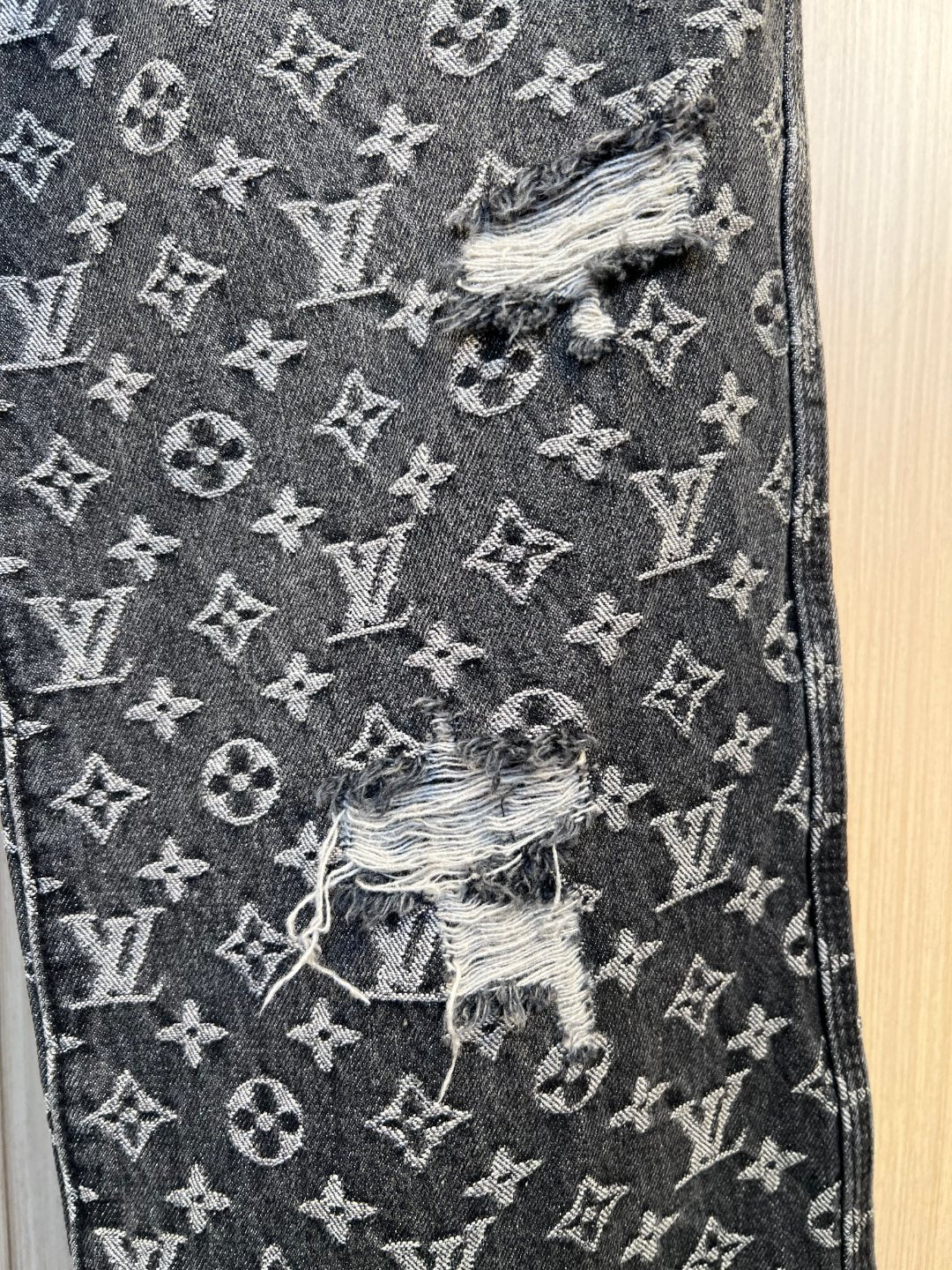 Louis Vuitton pants close-up showing monogram print and distressed embroidered patch