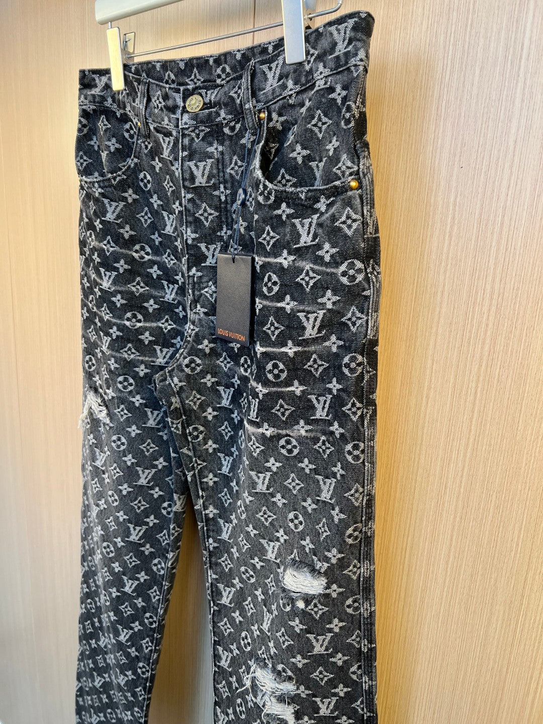 Louis Vuitton pants front view with monogram print, gold buttons, and patch detail
