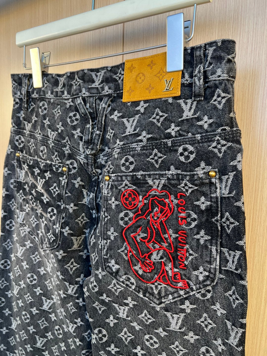 Louis Vuitton pants close-up showing monogram denim with large red embroidered graphic
