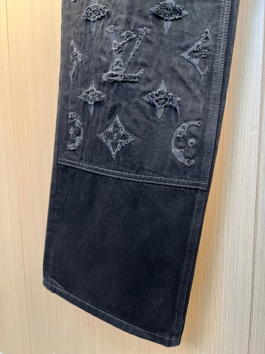 Dark denim pants closeup with monogram embroidery on leg panel
