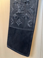 Dark denim pants closeup with monogram embroidery on leg panel