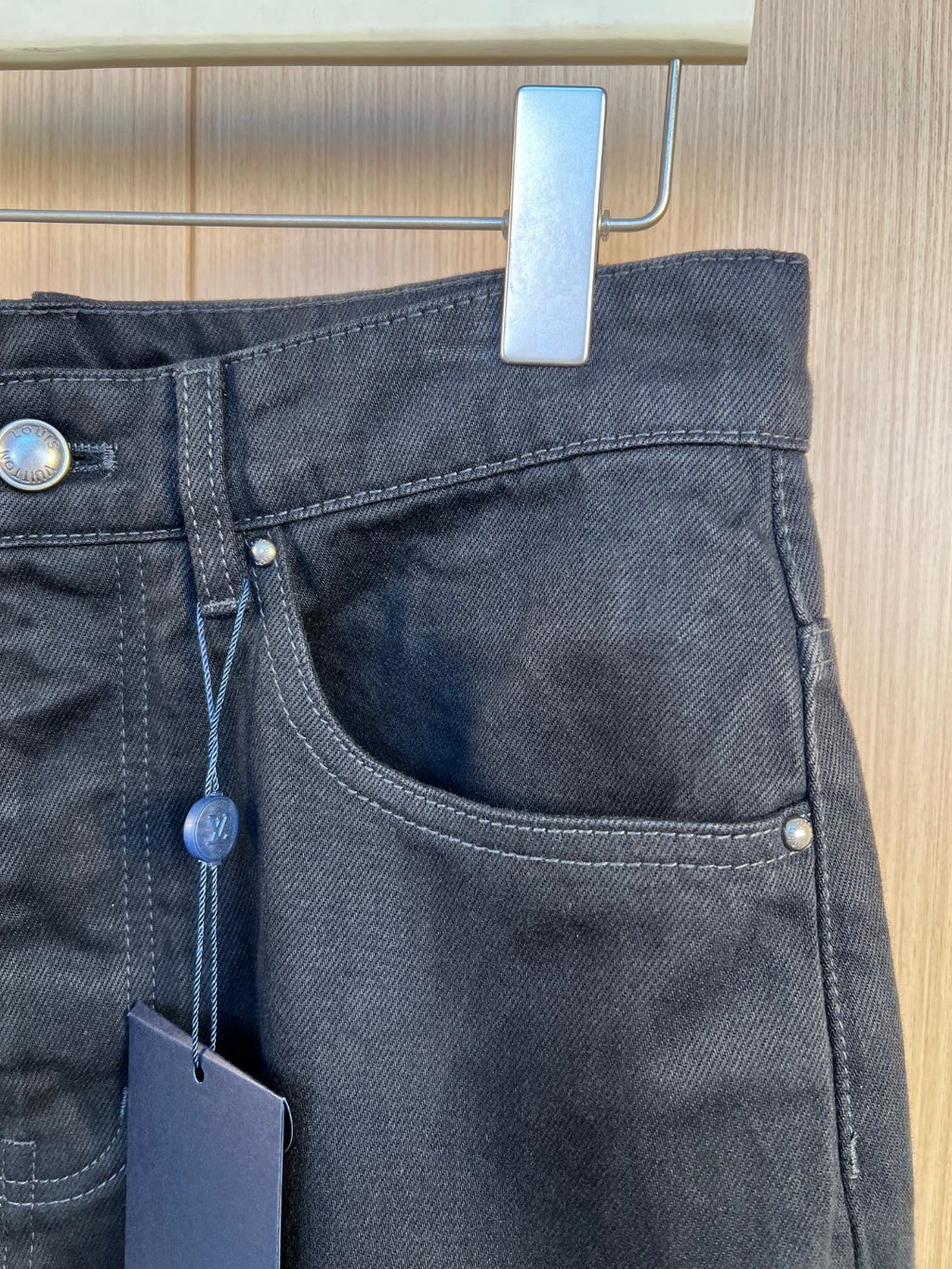 Dark denim pants waist with belt loops, button, and zip fly
