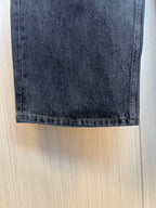 Hem of dark denim pants with visible stitching and cuff.
