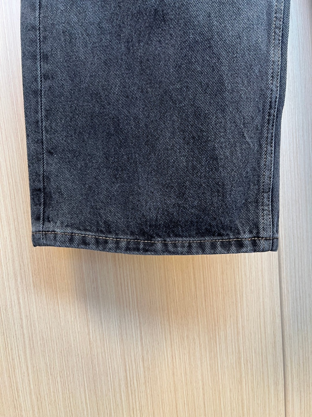 Hem of dark denim pants with visible stitching and cuff.