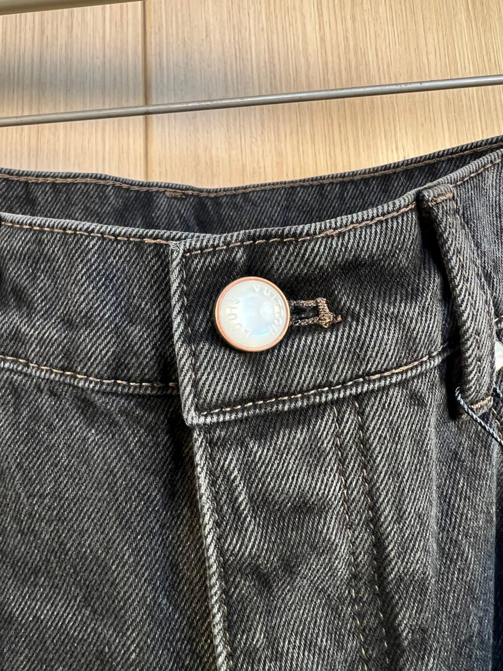 Denim waistband with button closure and circular LV logo badge.