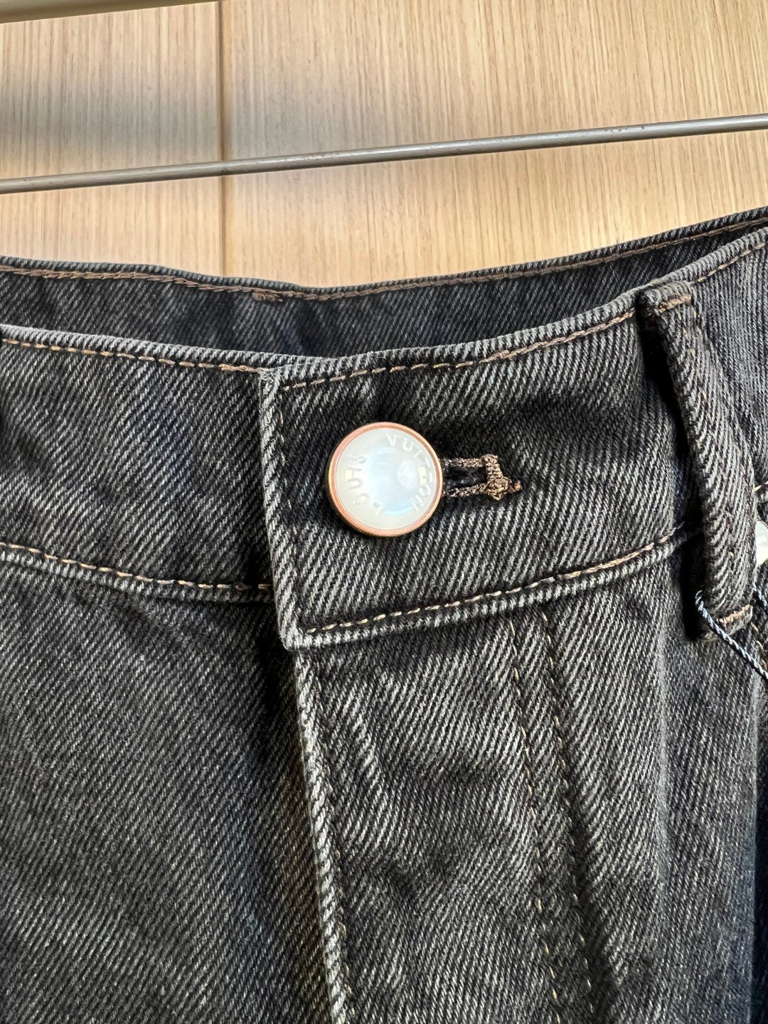 Denim waistband with button closure and circular LV logo badge.