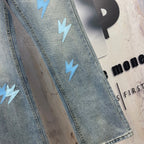 Light blue denim jeans leg with light blue lightning patches and stitched hem