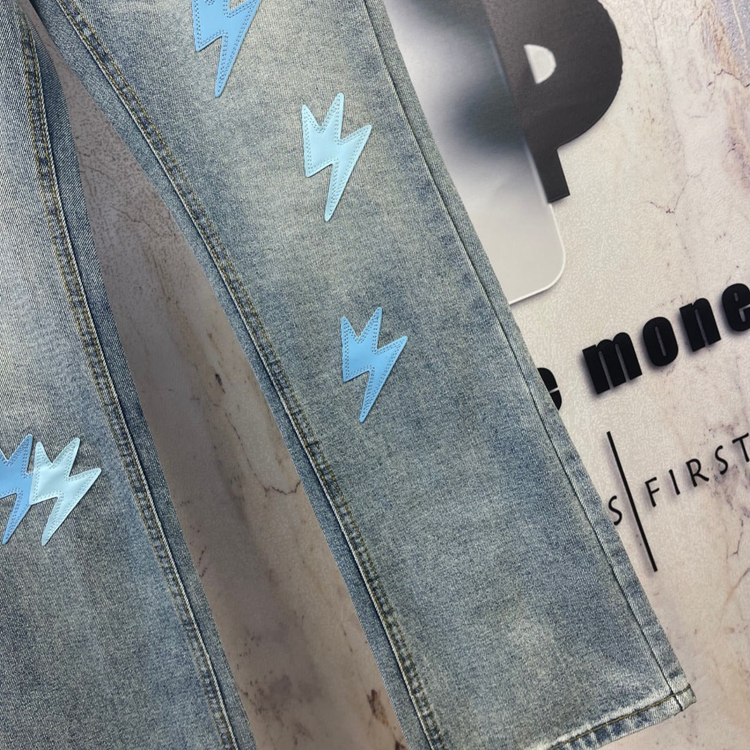 Light blue denim jeans leg with light blue lightning patches and stitched hem