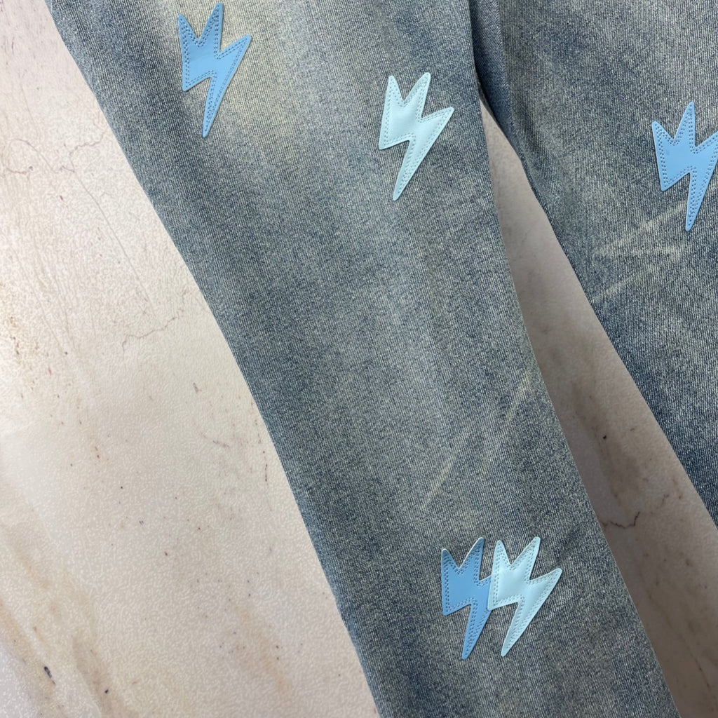 Light blue denim jeans close-up with light blue lightning patches on the legs