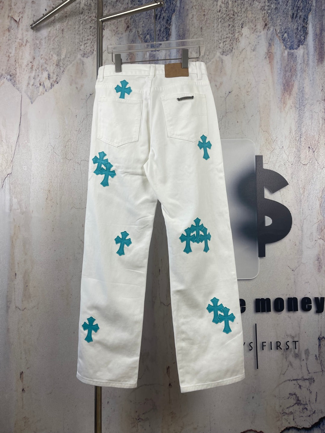 White denim pants with teal cross patches, front pocket view