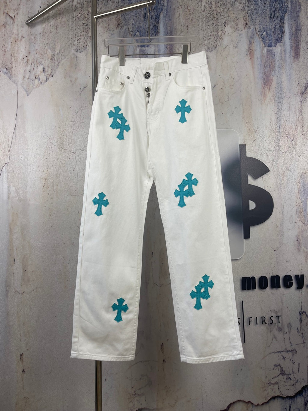 White denim pants with teal cross patches, front view