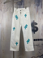 White denim pants with teal cross patches, front view