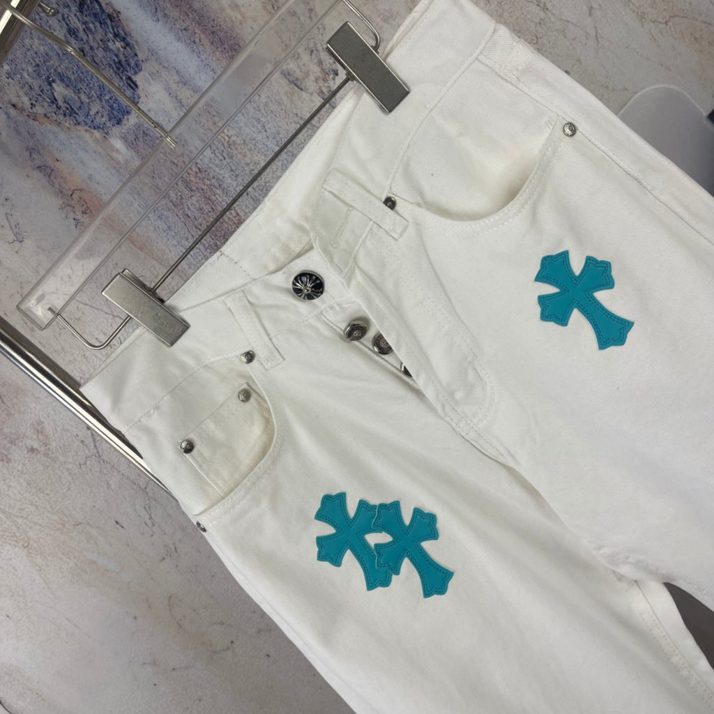 White denim pants with teal cross patches, angled front close-up