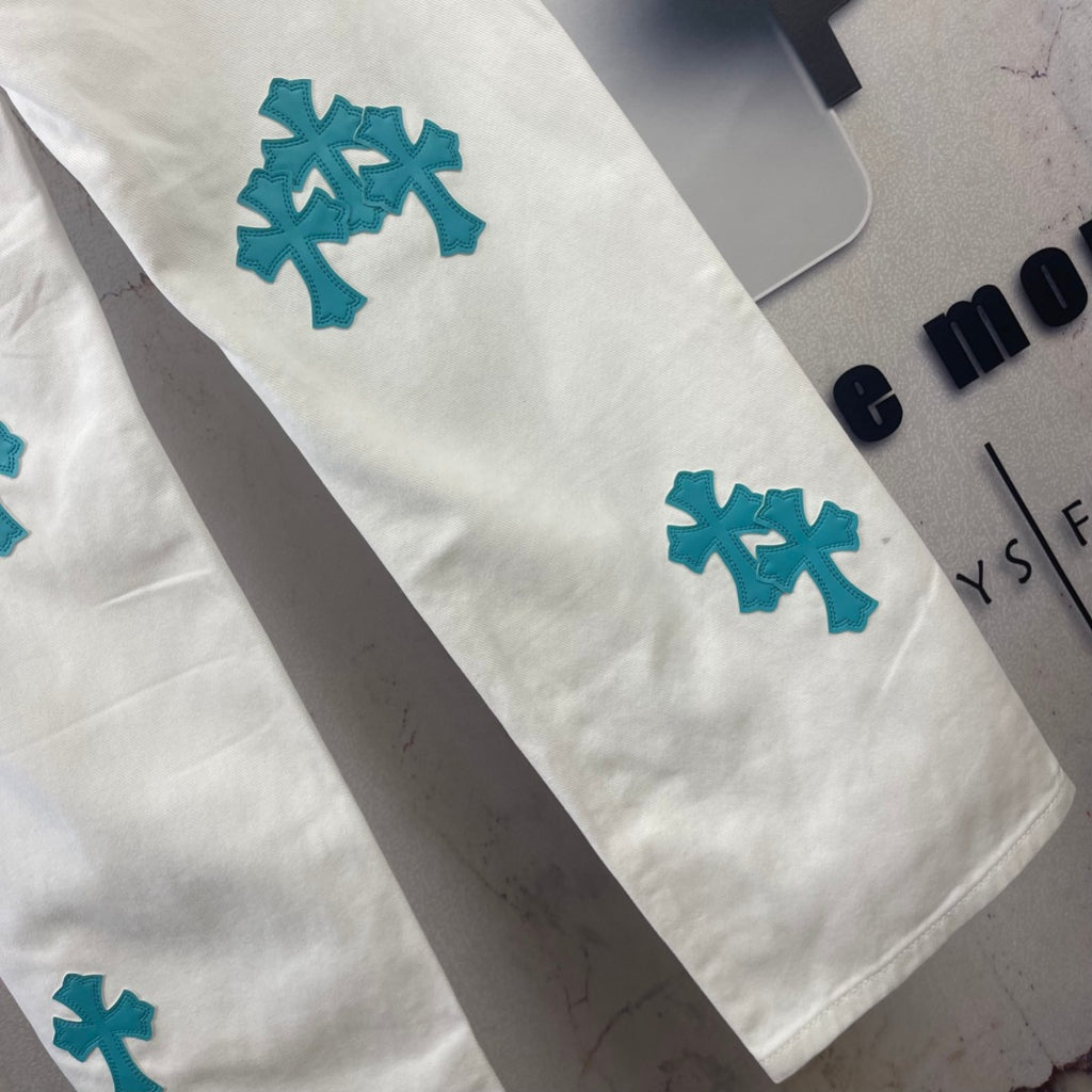 White denim pants with teal cross patches on leg, cropped side view