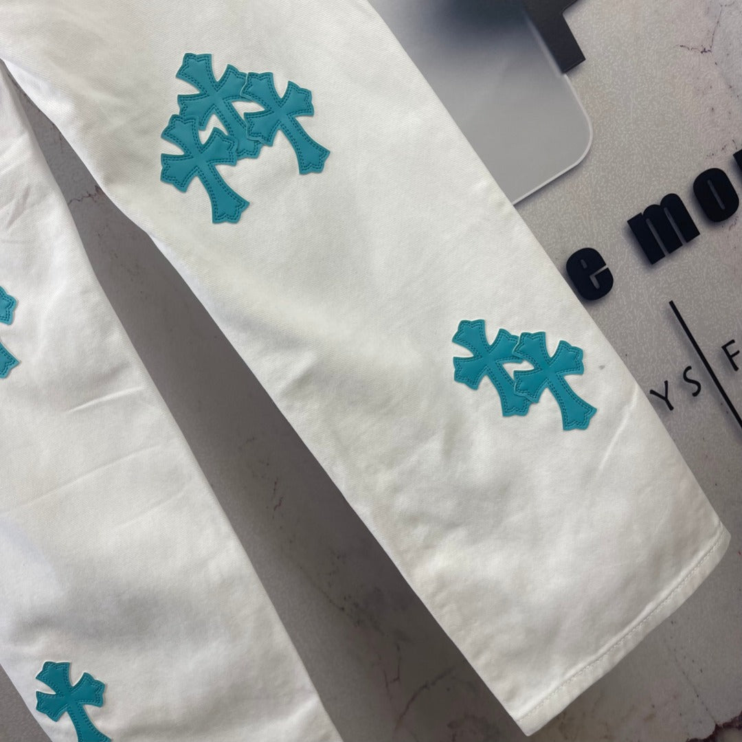 White denim pants with teal cross patches on leg, cropped side view