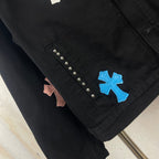 Black denim jacket sleeve detail with blue cross patch and diagonal rhinestone studs