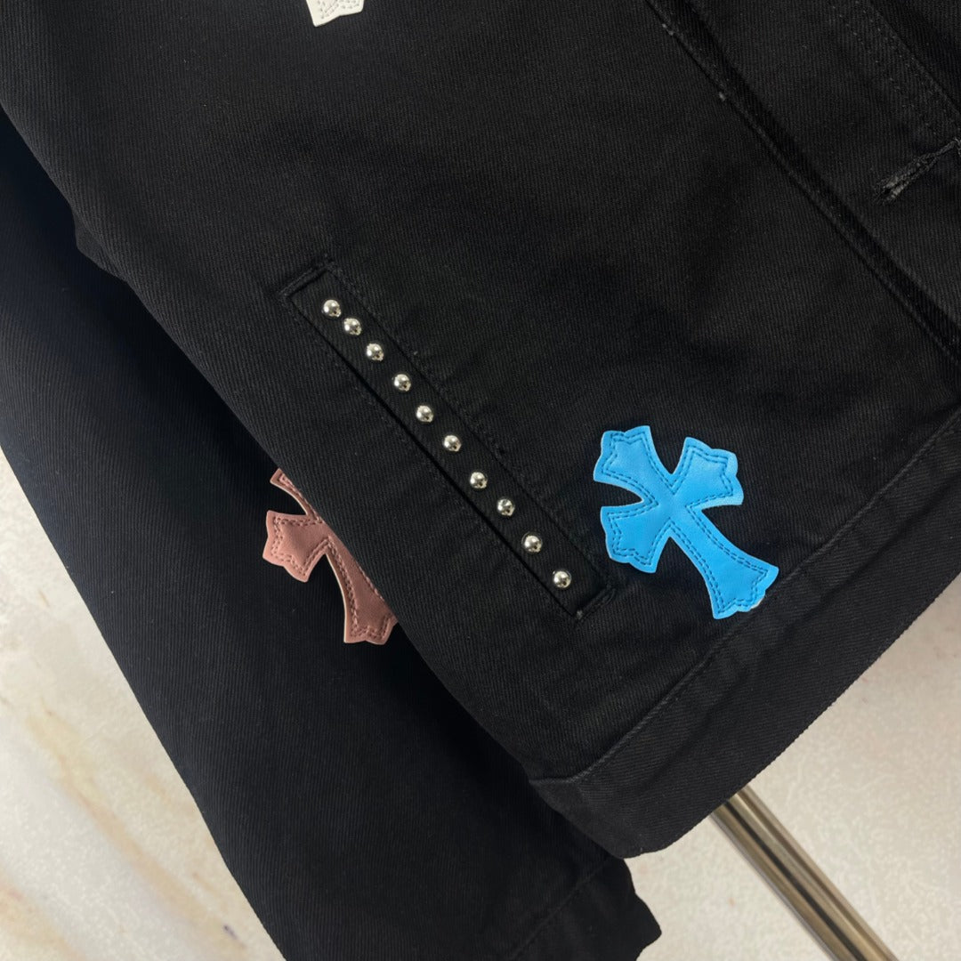 Black denim jacket sleeve detail with blue cross patch and diagonal rhinestone studs
