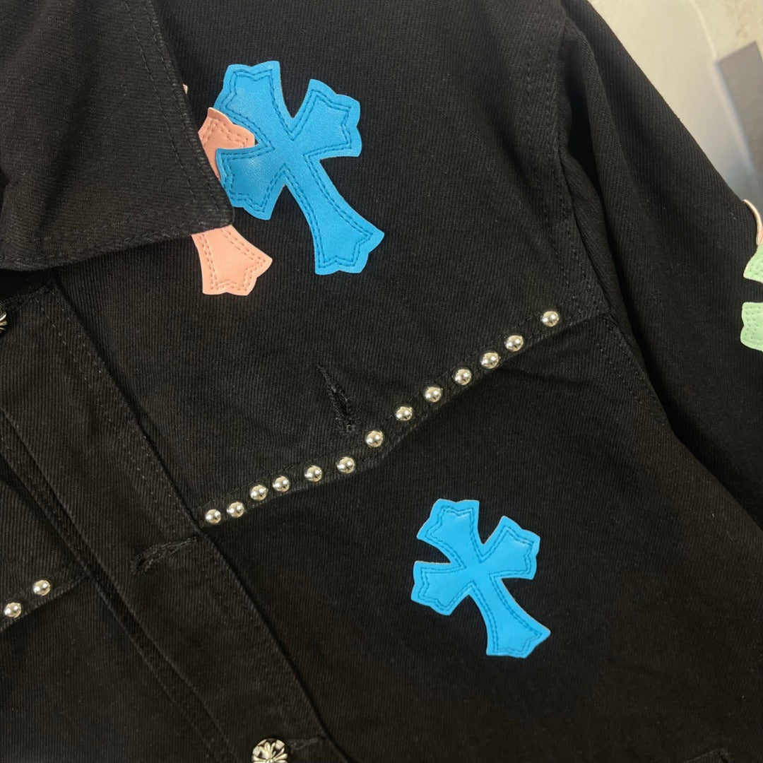 Black denim jacket close-up with blue cross, peach cross, and rhinestone diagonal trim
