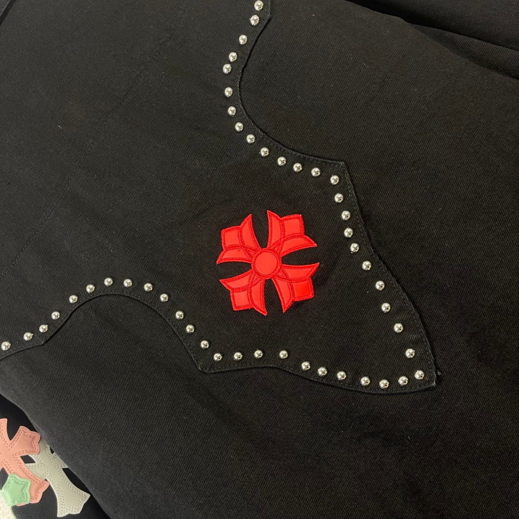 Black denim jacket collar close-up with red floral emblem and rhinestone border