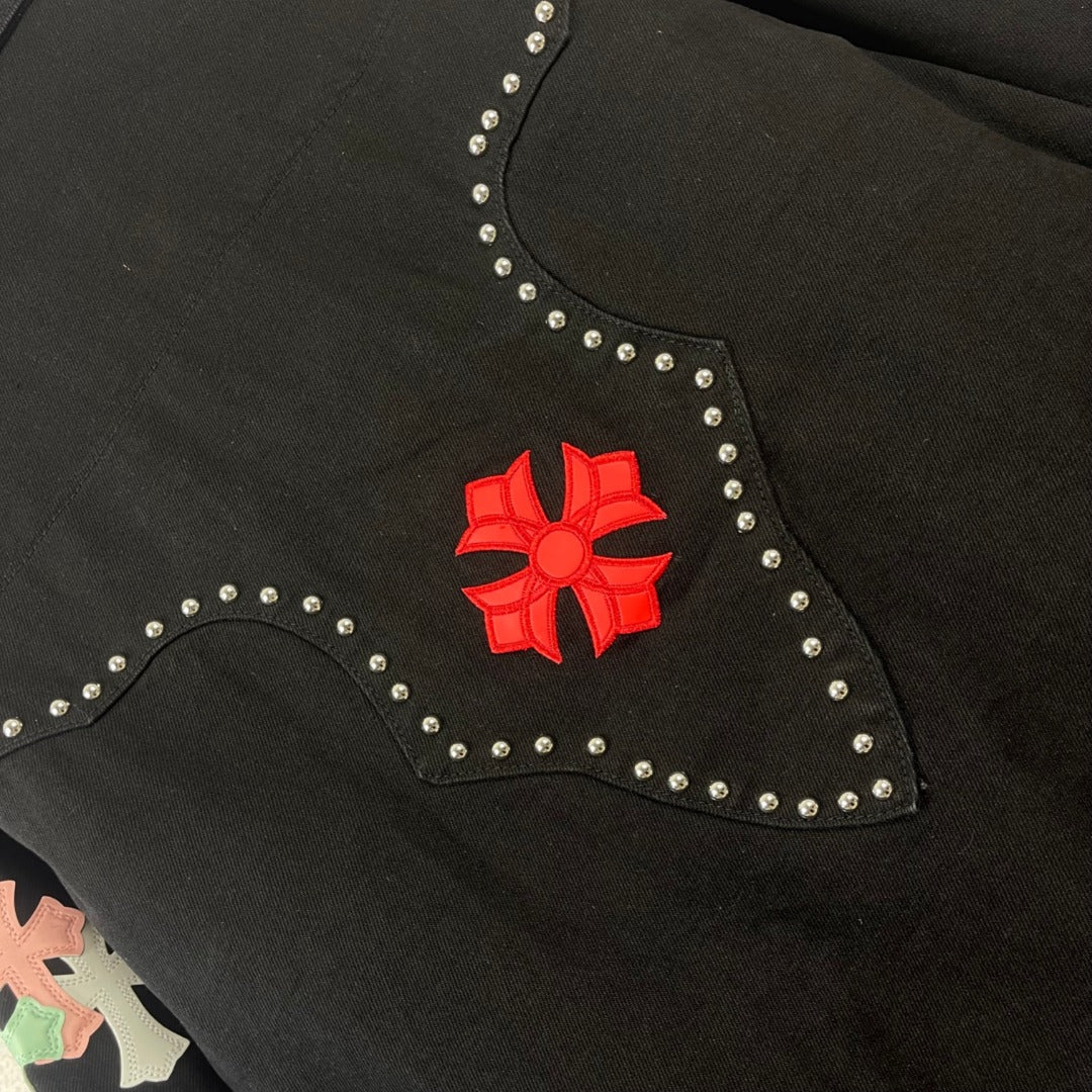 Black denim jacket collar close-up with red floral emblem and rhinestone border