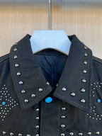 Dark denim jacket collar with silver studs and blue button accent at neckline.