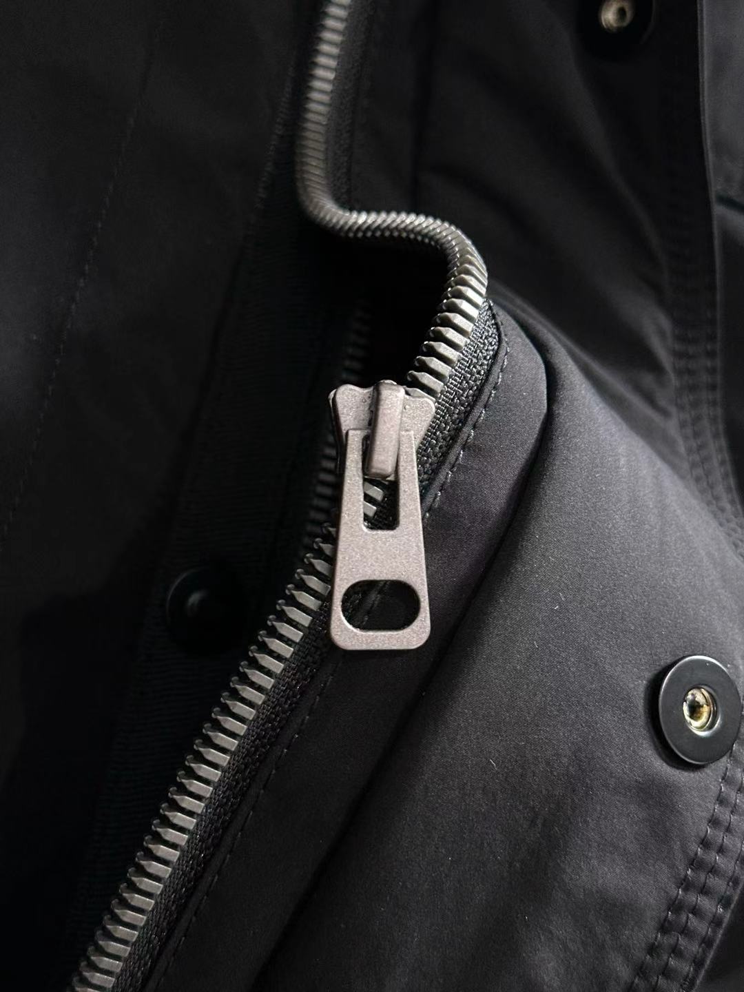 Dior long black jacket detail with front zipper, snap placket, and metal buttons