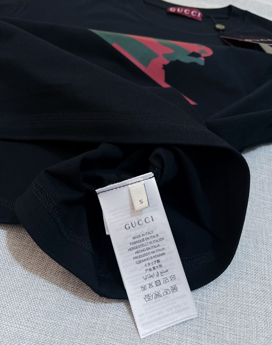 Black Gucci T-shirt fabric close-up with size label at inner neckline