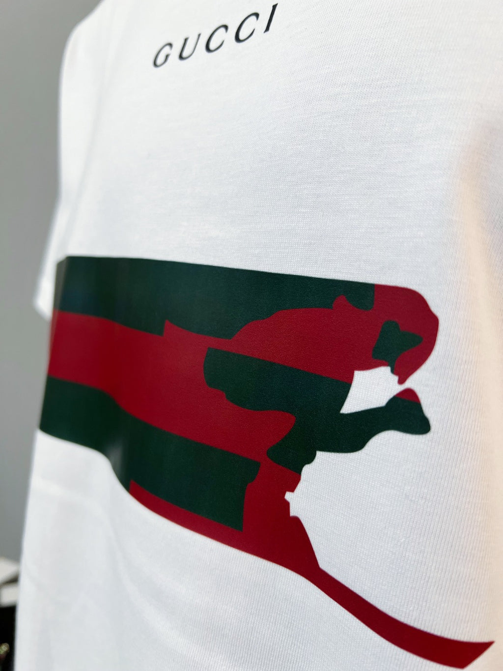 White Gucci T-shirt chest graphic close-up with red/green striped animal silhouette