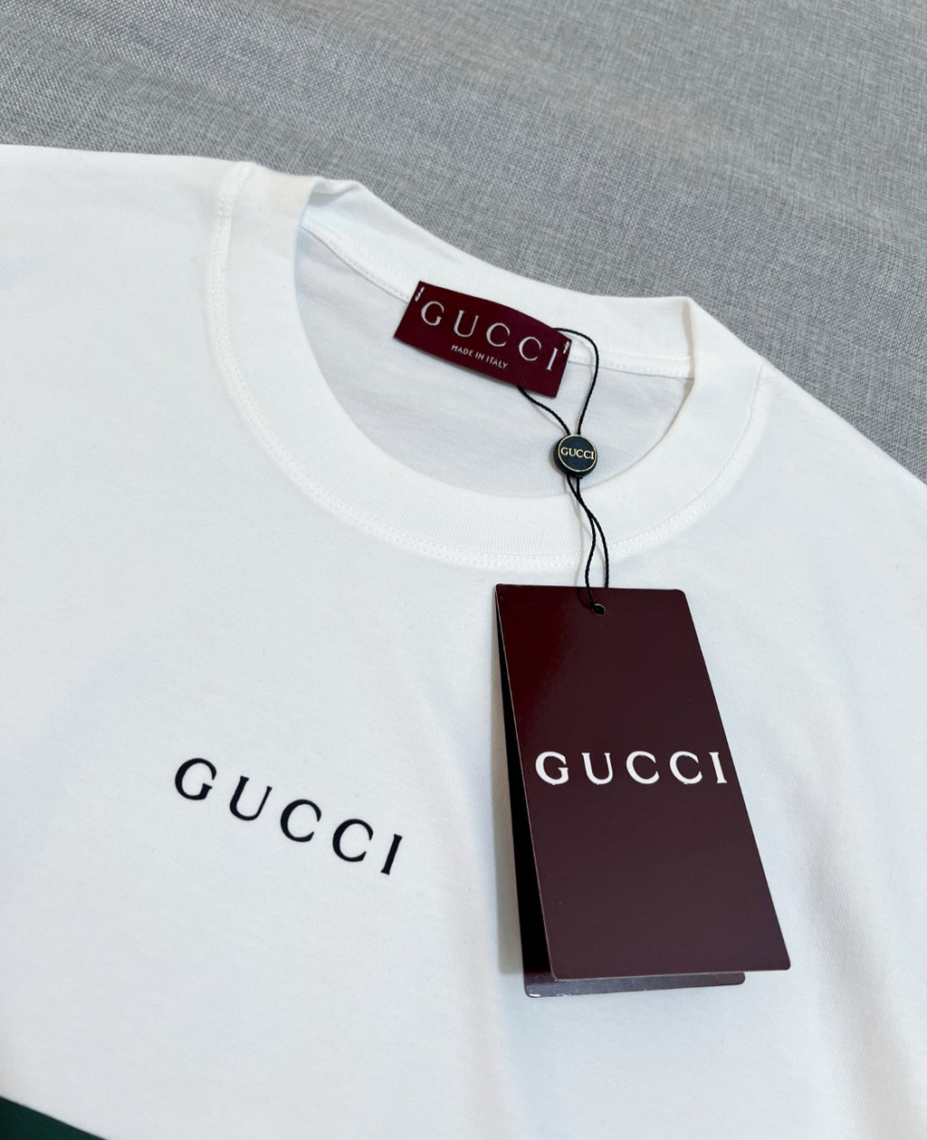 White Gucci T-shirt collar with “GUCCI” print and attached maroon product tag