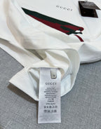 White Gucci T-shirt fabric close-up with size label and partial red/green graphic