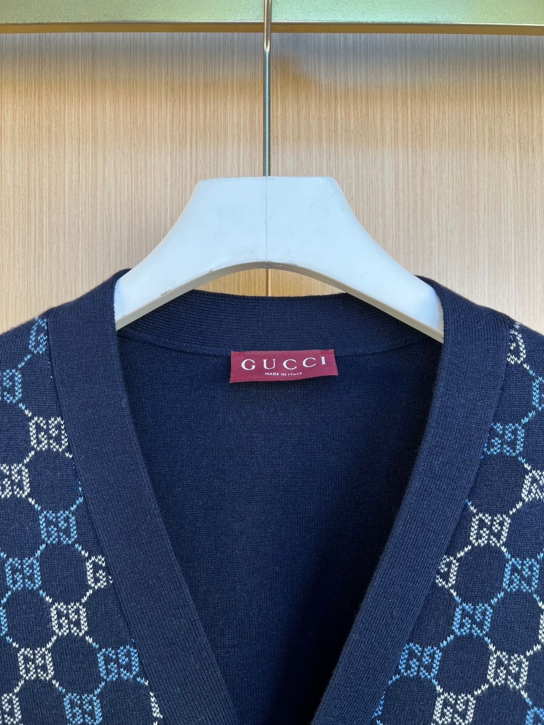 Gucci knit cardigan neckline close-up with pink brand label and GG pattern