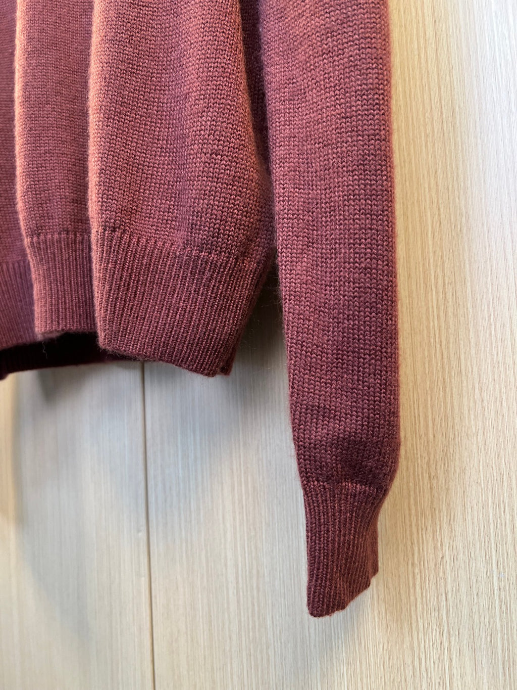 Burgundy knit sweater sleeves and ribbed cuffs, close-up view