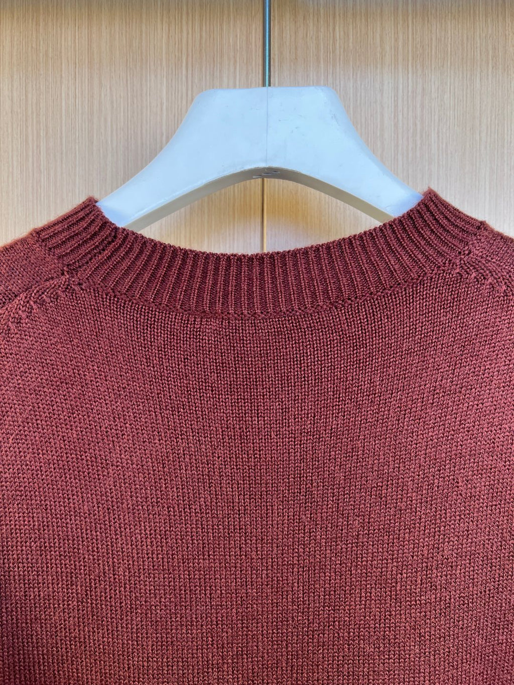 Burgundy knit sweater crewneck close-up with textured ribbed collar