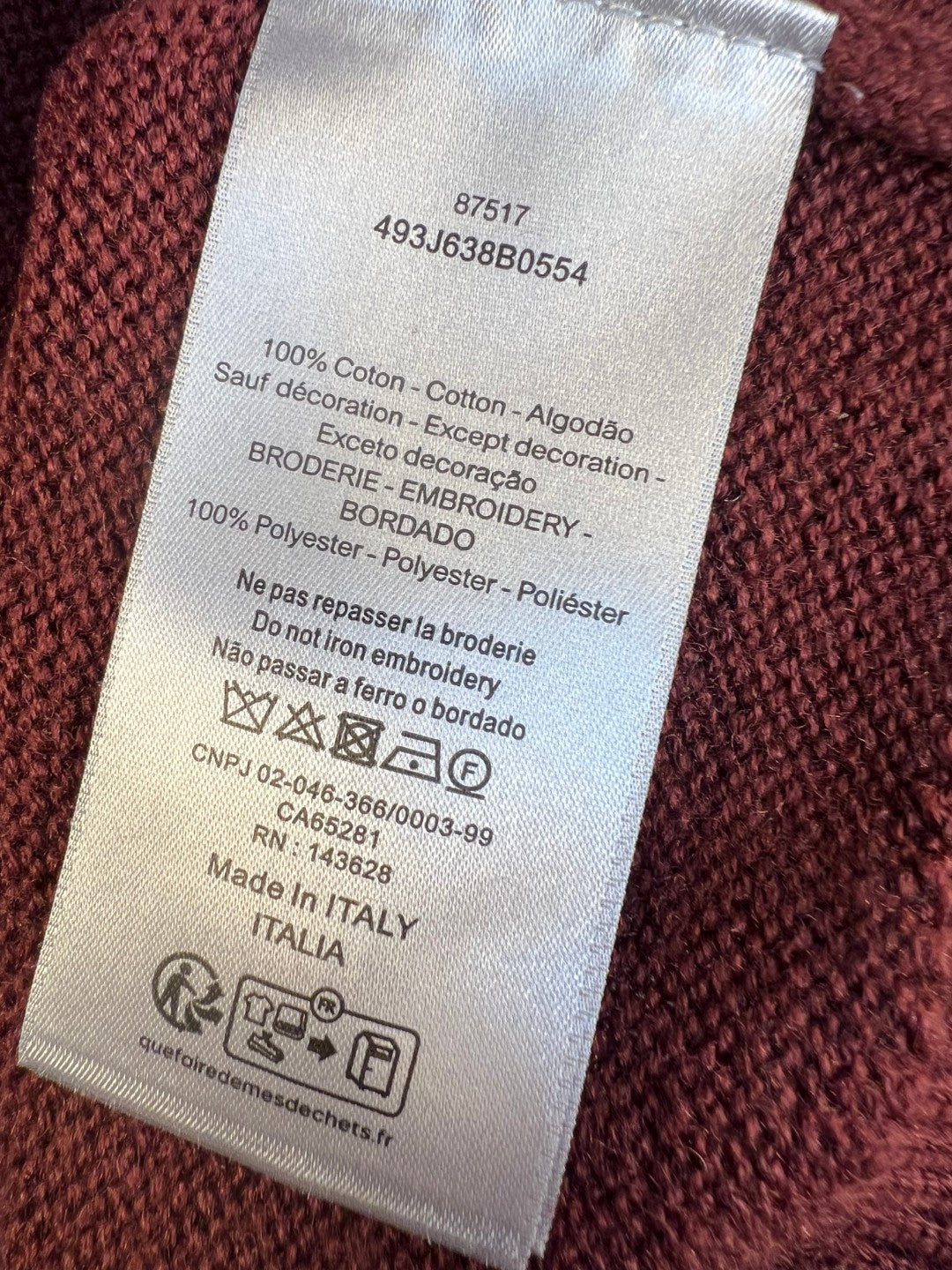 Burgundy knit sweater care label with material and country info