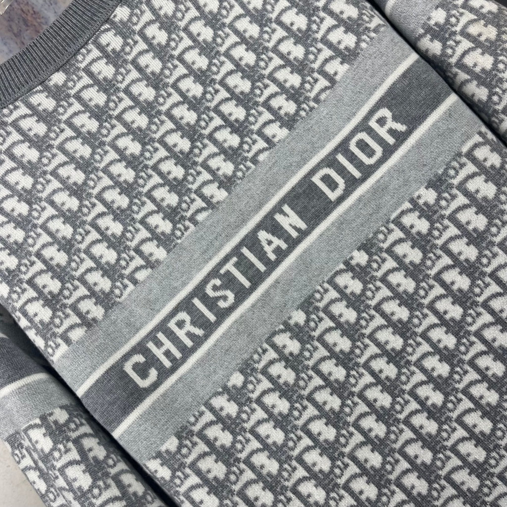 Close-up of Dior logo stripe on gray crewneck sweater, monogram pattern fabric