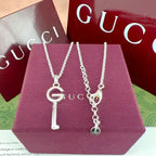 Gucci G key pendant necklaces on purple box, silver-tone heart and circular charms