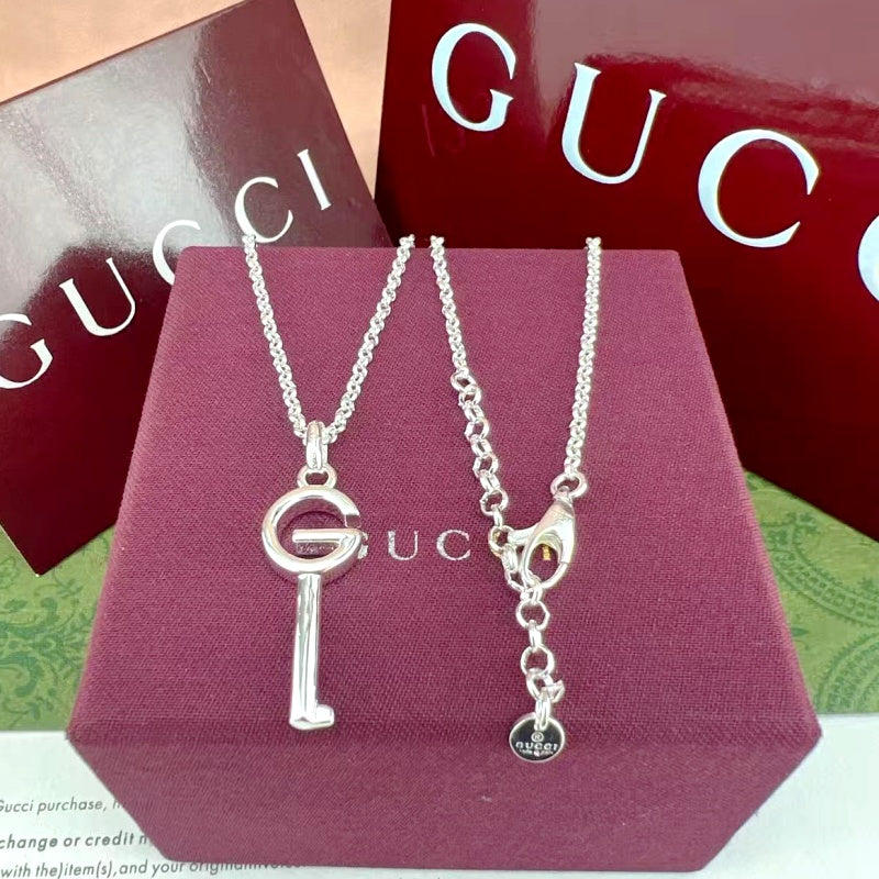 Gucci G key pendant necklaces on purple box, silver-tone heart and circular charms