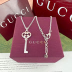 Gucci pendant necklaces with G heart and key charms on purple jewelry box
