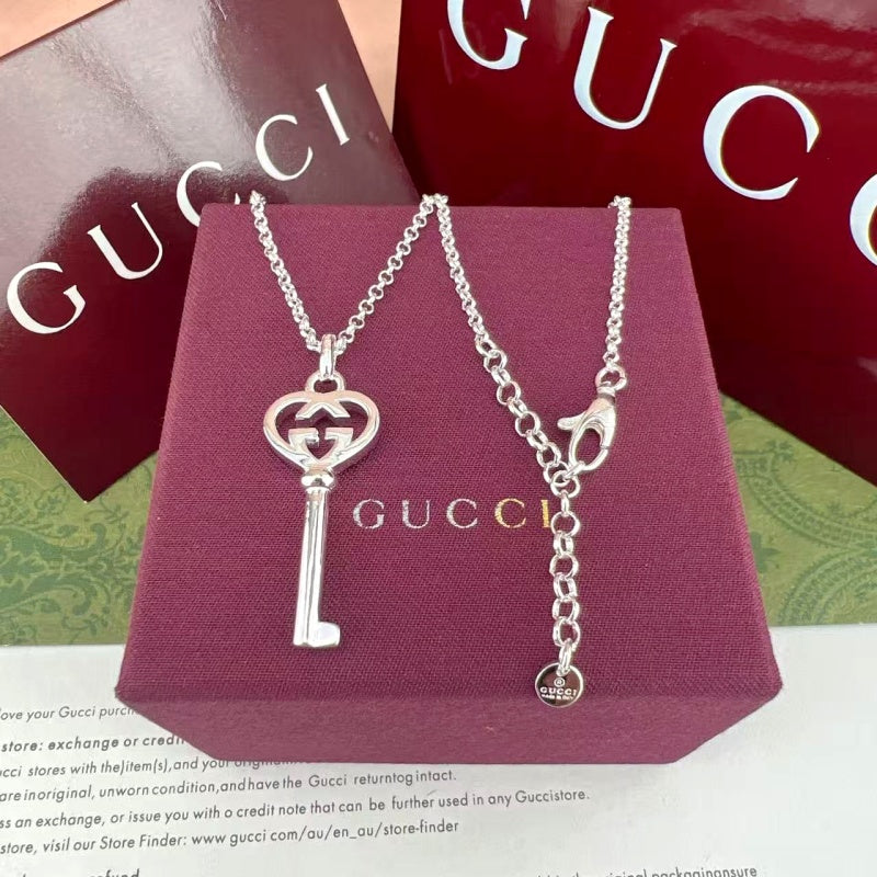 Gucci pendant necklaces with G heart and key charms on purple jewelry box