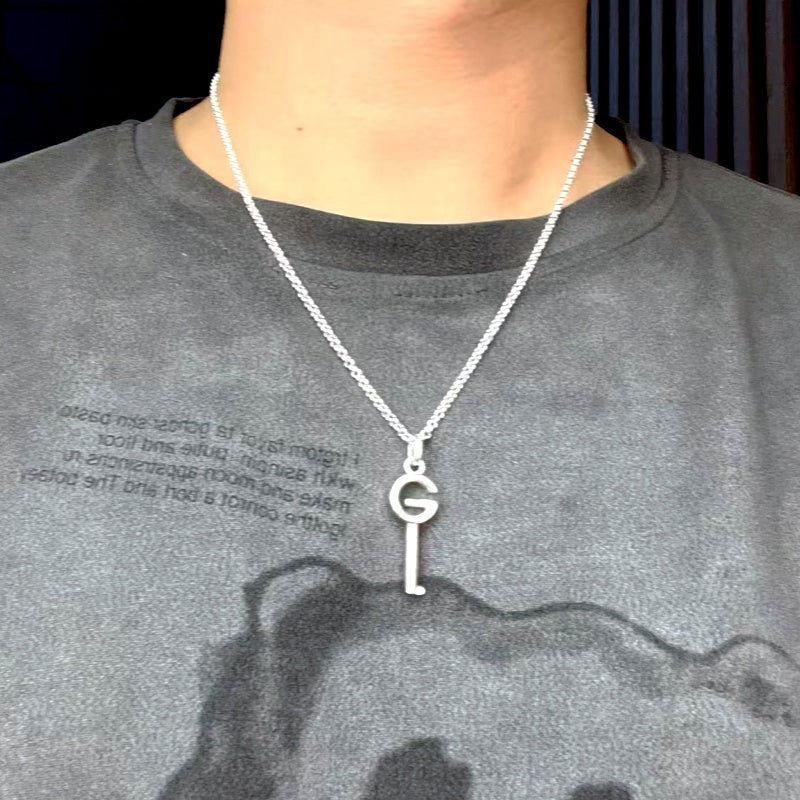 Silver-tone pendant necklace on model with G charm and key drop