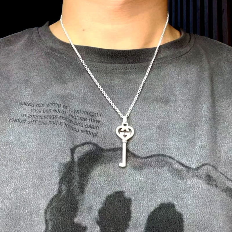 Silver-tone pendant necklace on model with heart G charm and key drop