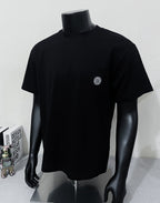 Black short-sleeve T-shirt with crew neck and small circular chest logo patch