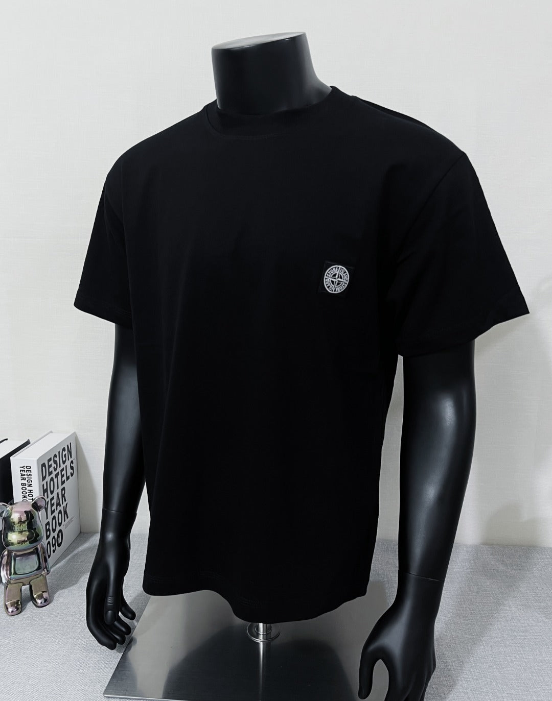 Black short-sleeve T-shirt with crew neck and small circular chest logo patch
