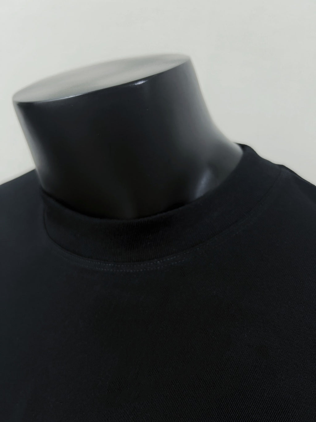 Black crew-neck T-shirt neckline close-up on mannequin