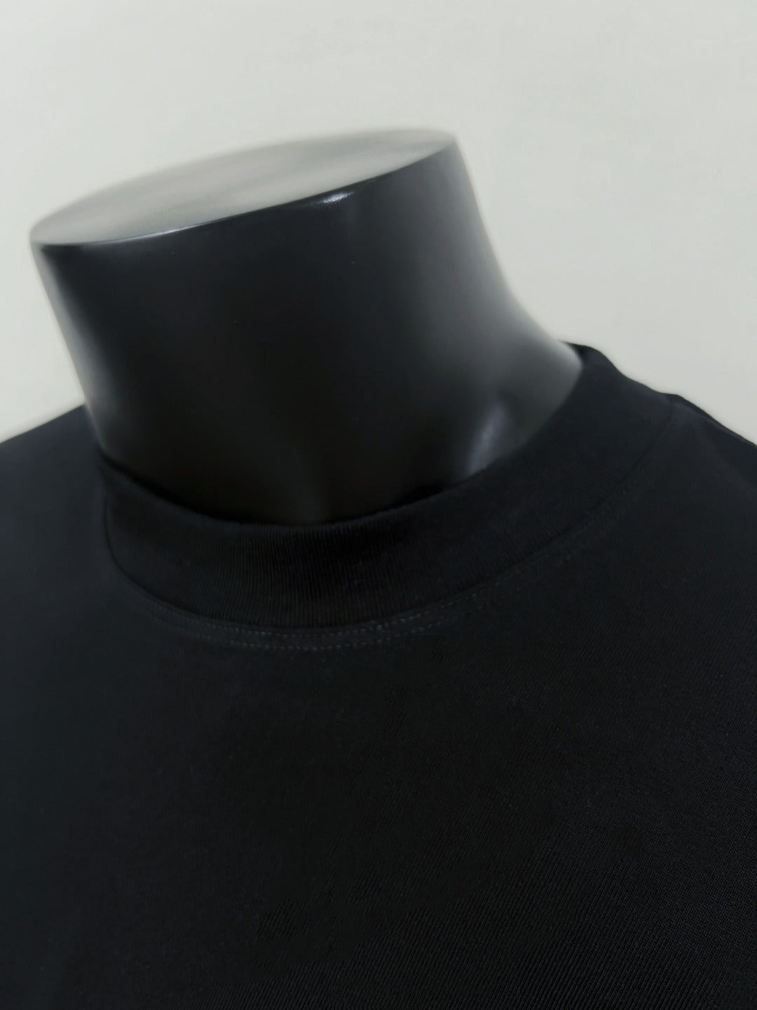 Black crew-neck T-shirt neckline close-up on mannequin